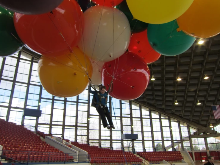 a person is suspended by a number of balloons