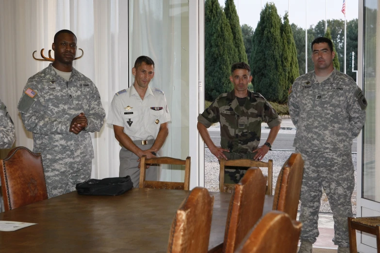 men in military uniform standing in front of a wooden table