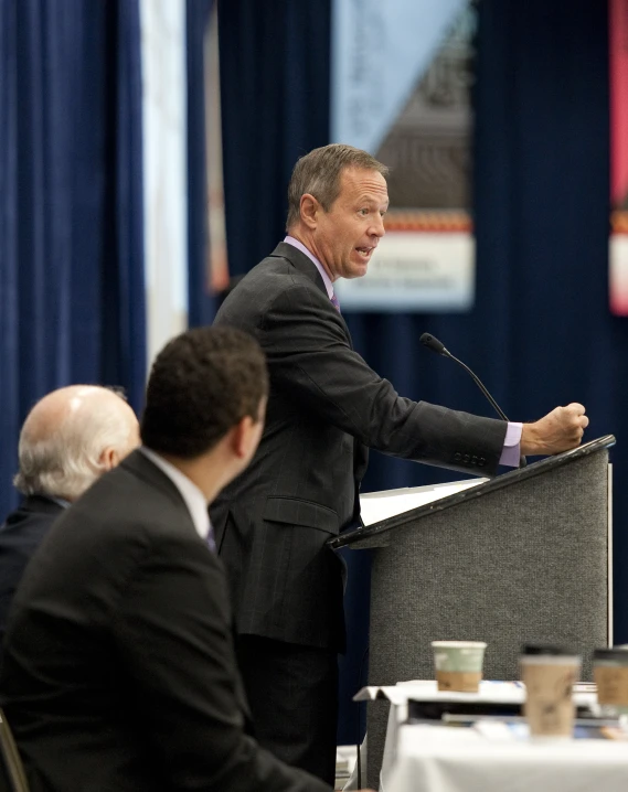 a man stands at a podium speaking to people