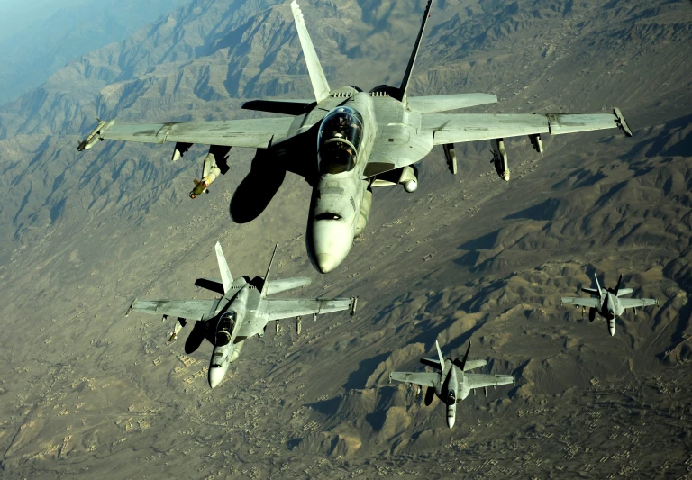 fighter jets flying over mountains and barren terrain