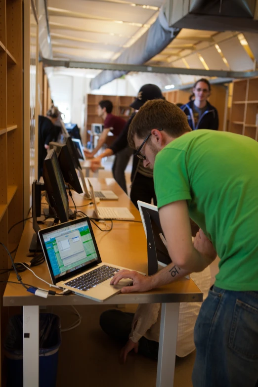 there is a man looking at a computer on a desk