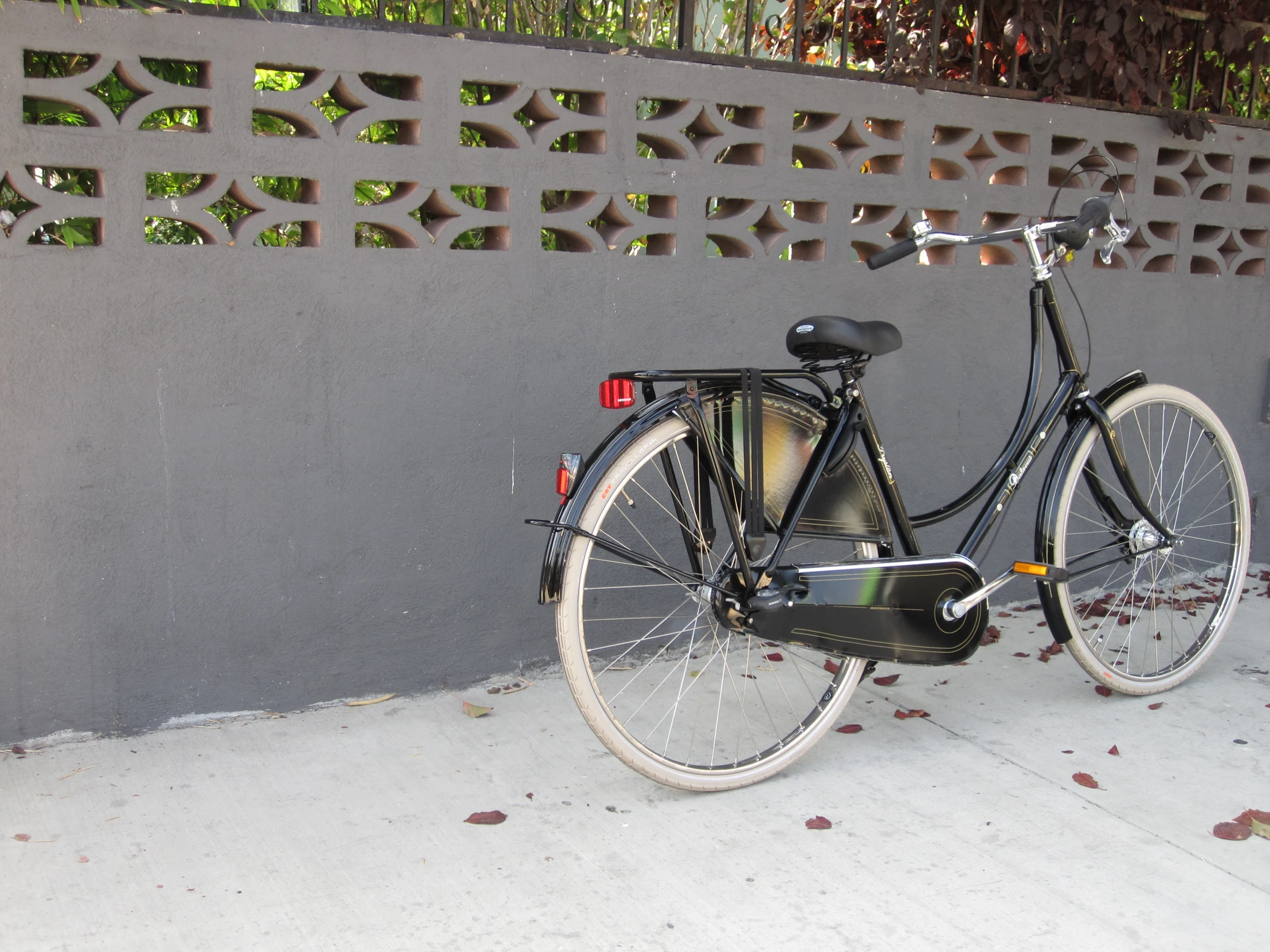 a black bicycle is parked next to a gray wall