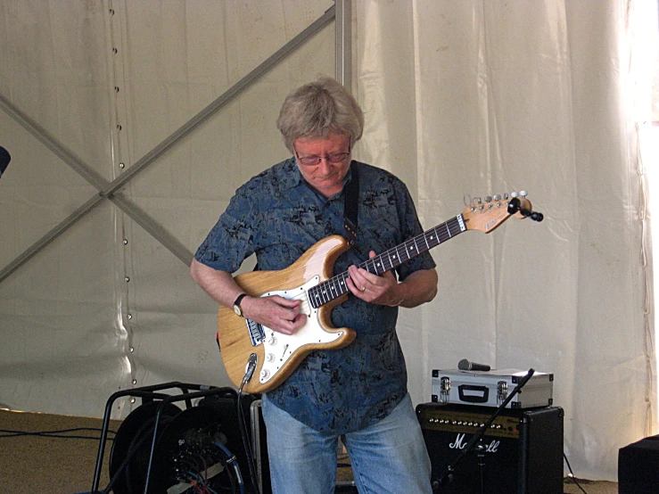 a man holding a guitar up while standing in front of a microphone