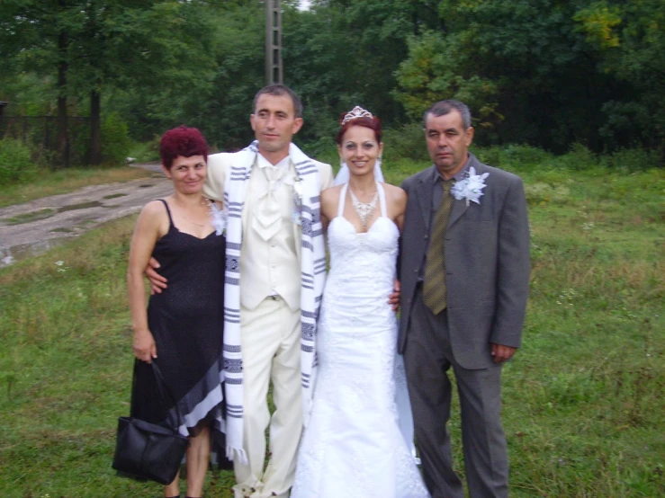 three men and two women standing beside each other in front of a cross