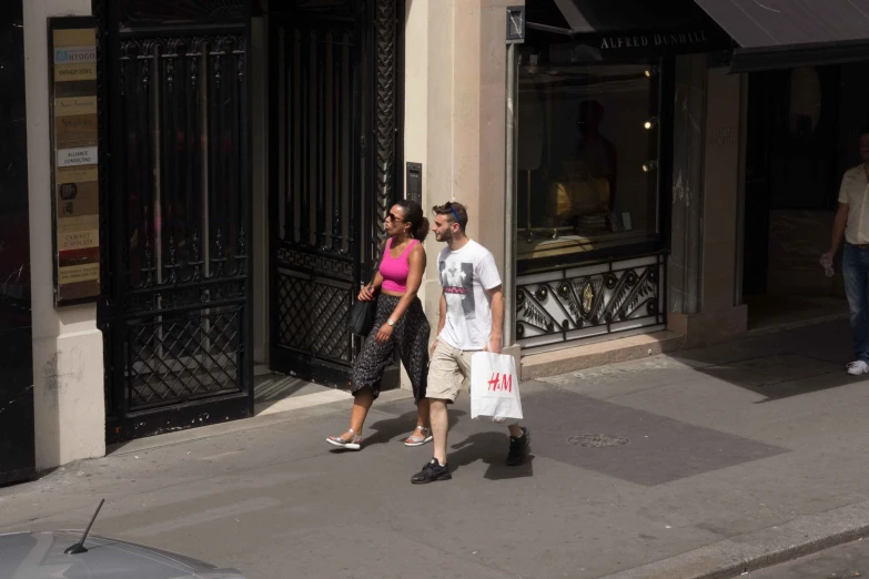 a man and woman walking down a street holding bags