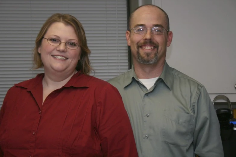 two people posing for the camera in their office