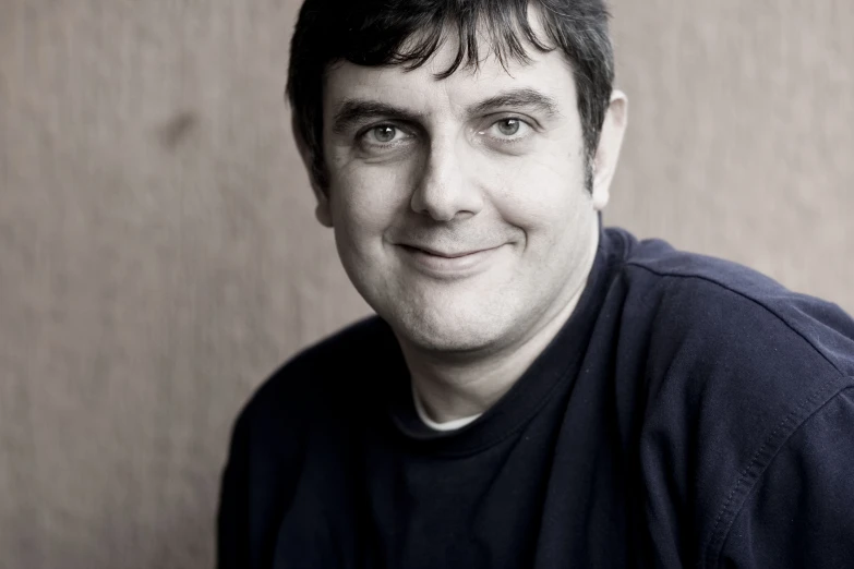 man sitting on brown surface, smiling at camera