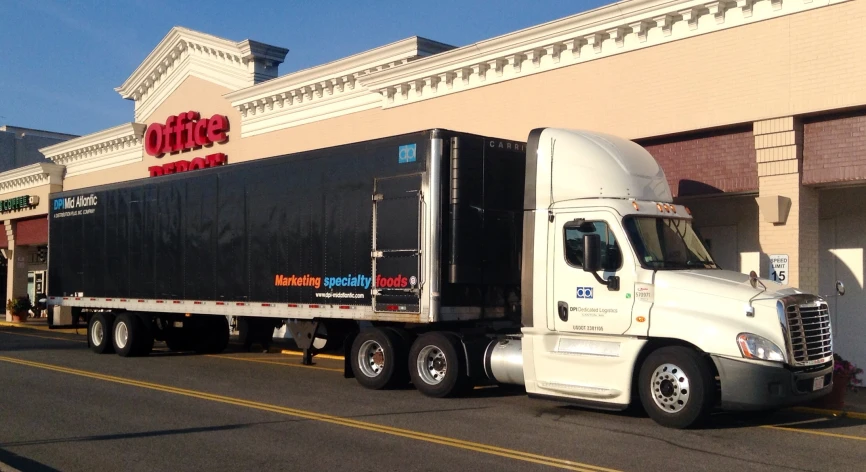 a semi with a black trailer trailer in front of store