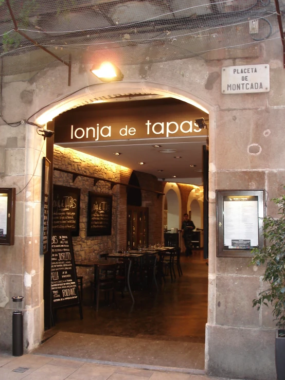 a restaurant in stone building with wooden tables and a black clock