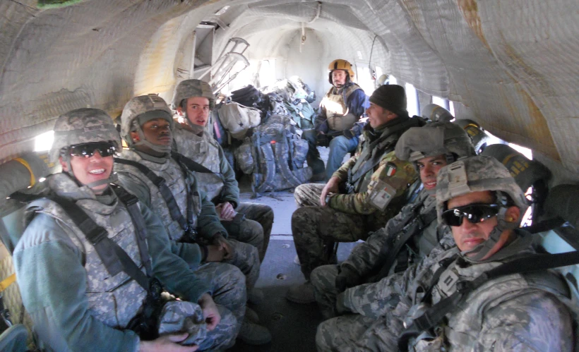 a group of men in fatigues sitting on a plane