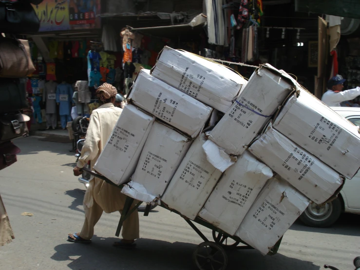 the man is hing a cart of cardboard boxes