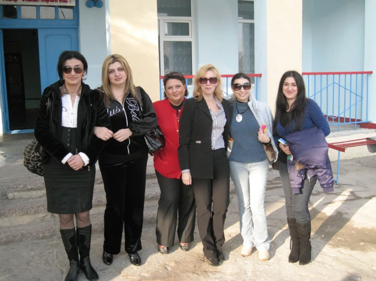 nine women standing on steps near a building