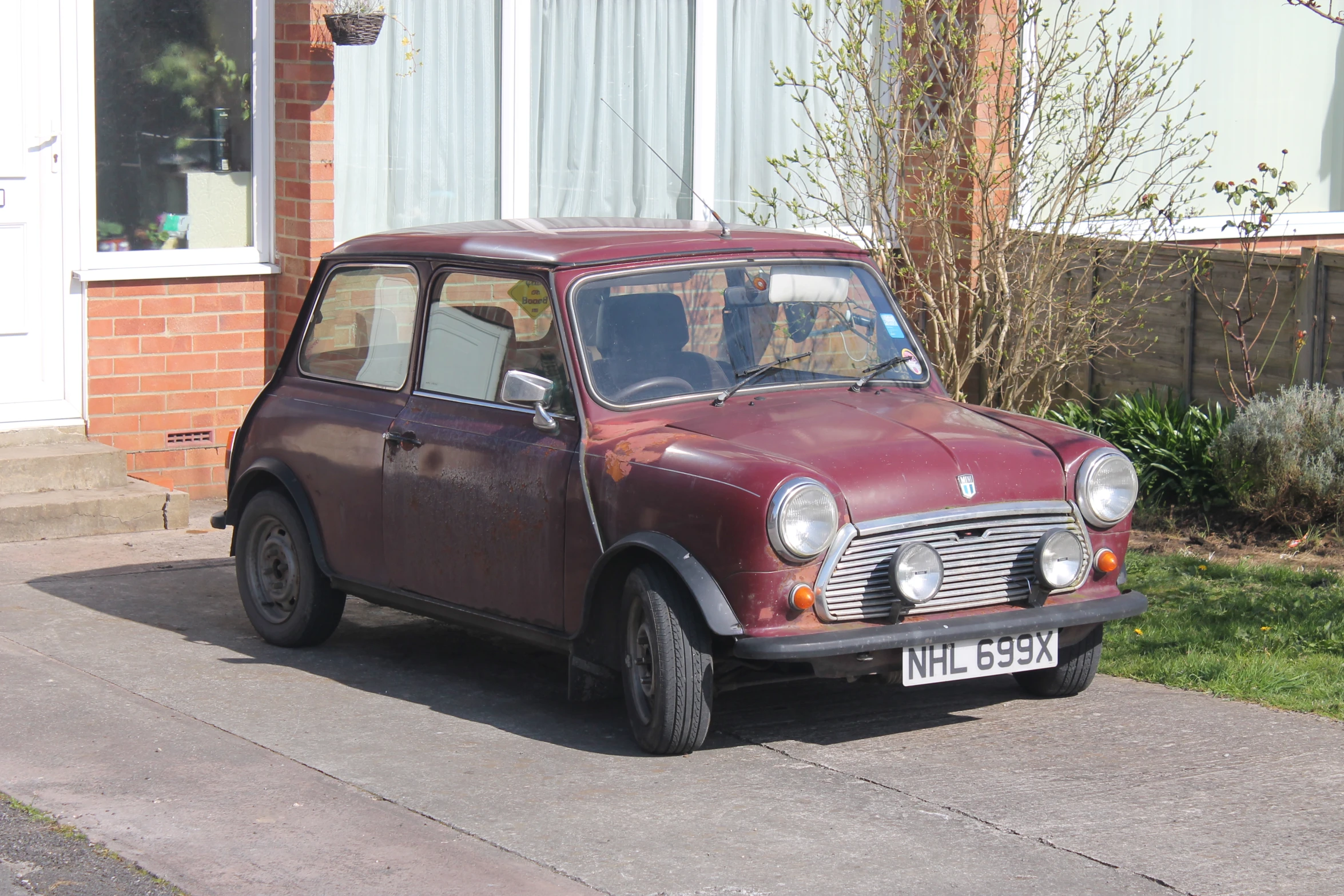 an old red car parked in the road outside a house