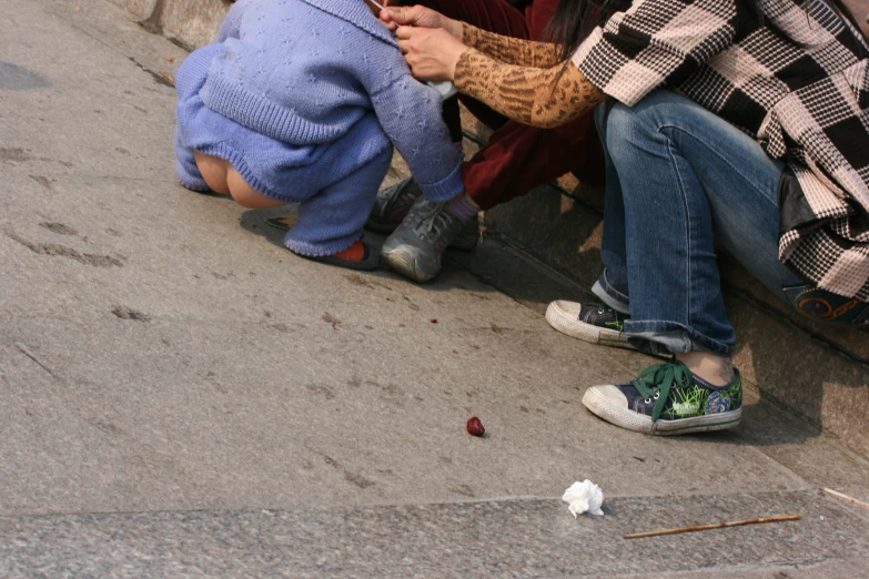 young children on sidewalk near trash can next to woman and child