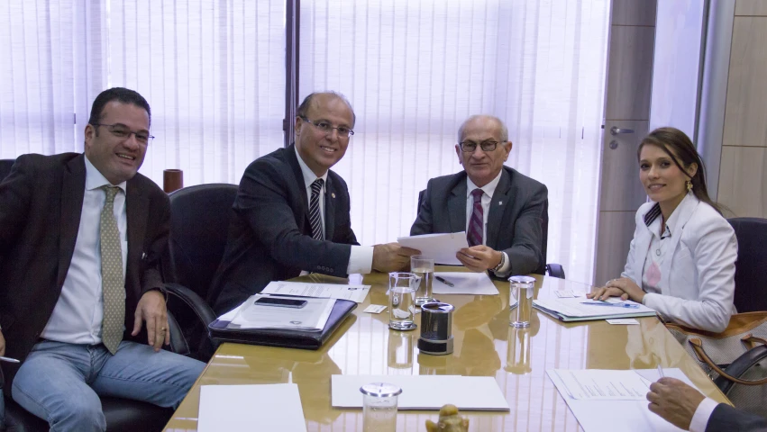 group of men and women sitting around table in office