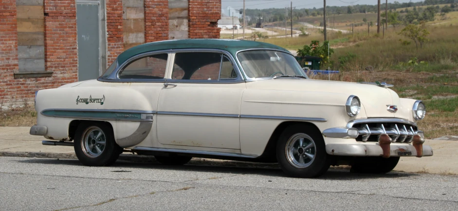 an old car is sitting in front of a rusted building