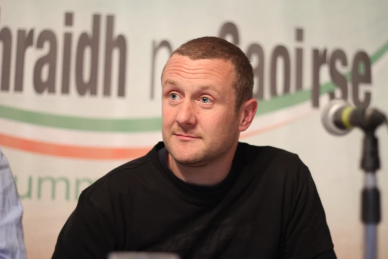 a man sitting in front of microphone while talking to someone