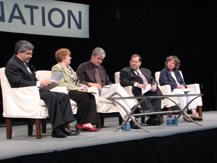 several people sitting down at an event and one has a phone