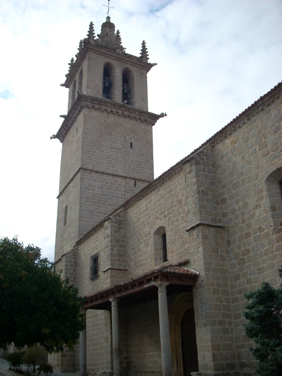 large old stone building with bell tower and green trees