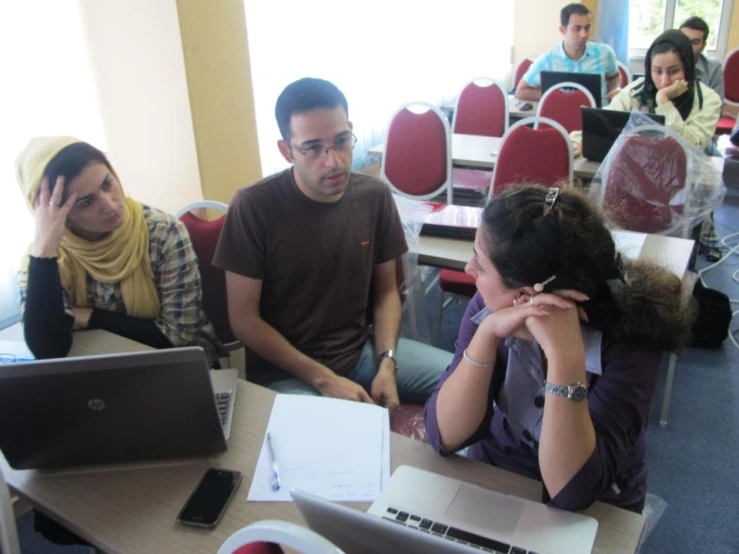 four people gathered at a table working on laptop computers