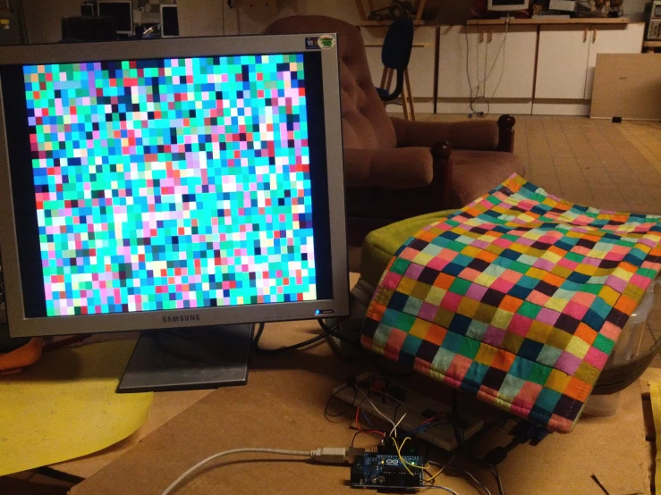 a computer screen sitting next to a very big blanket