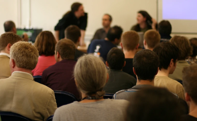 a group of people sitting in front of a speaker