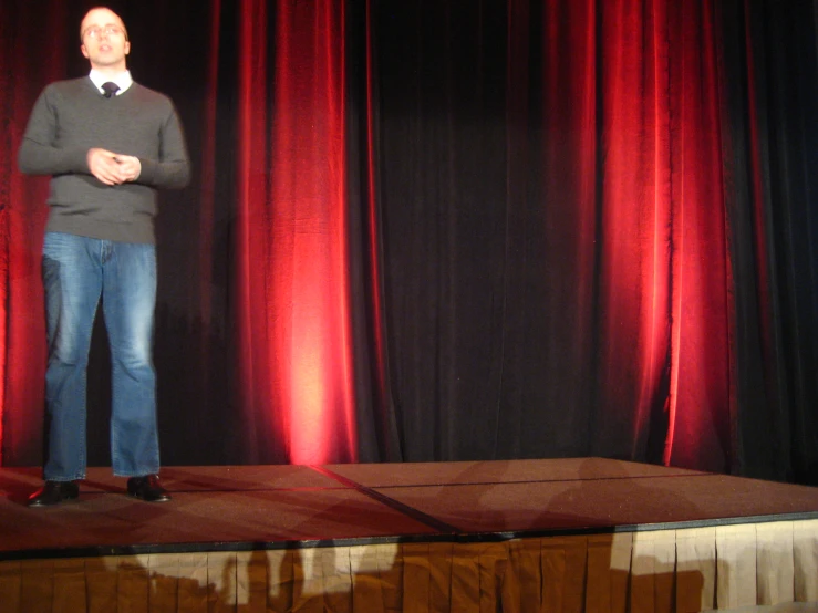 a man stands on stage with hands folded