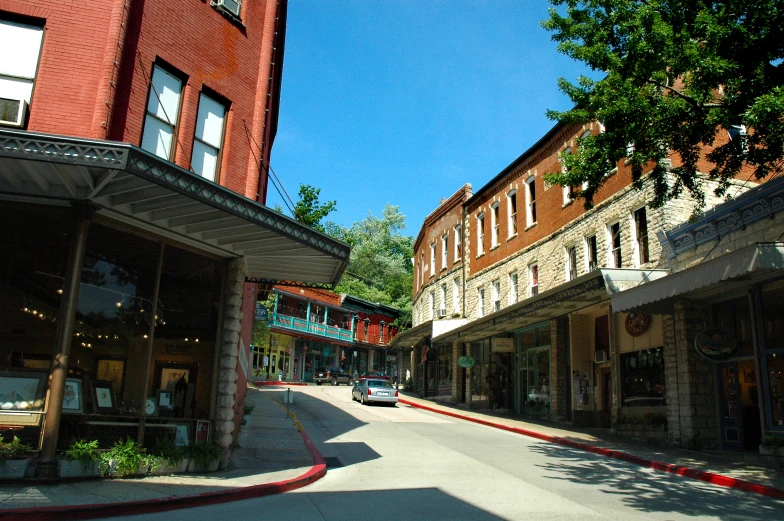 a car driving through the street with stores in front