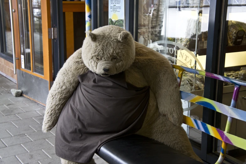 a large teddy bear sitting on top of a black bench