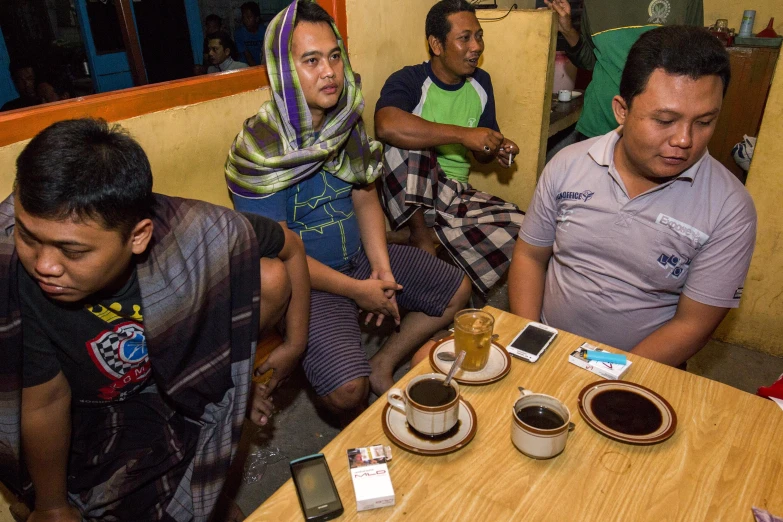 a group of men sitting around a table eating