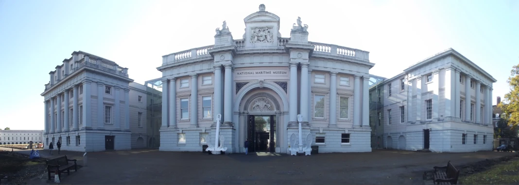 the white building has two clocks and some benches