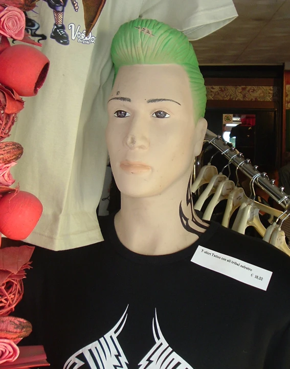 a male mannequin with lime green hair stands by several clothing hanging