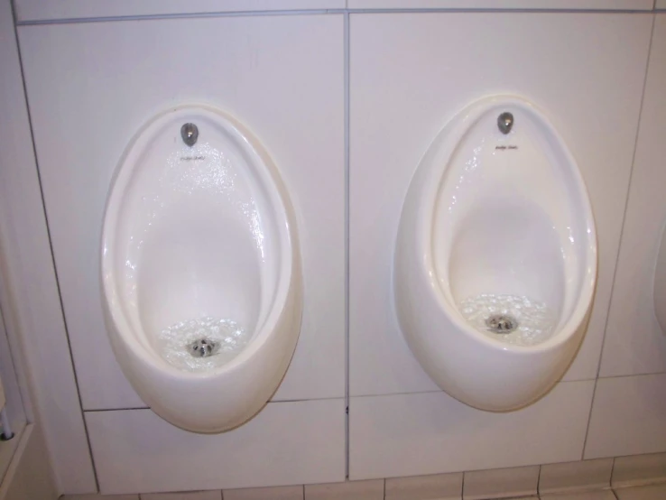 two urinals side by side on a tile wall