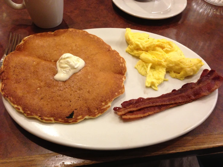 this plate has bacon, pancakes and eggs on it