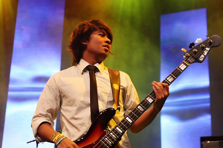 a young man holding his guitar to take it on stage