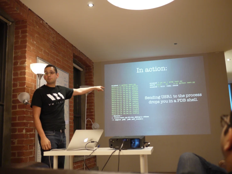 a man stands in front of a projector while pointing at soing