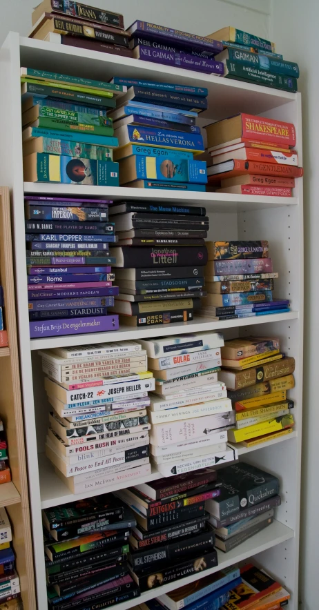 several shelves filled with books and dvds on a white shelf