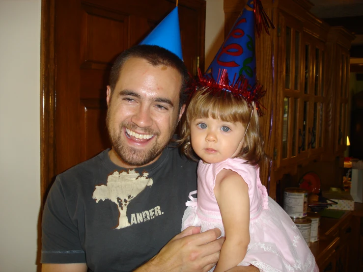 a man holding a  wearing a party hat