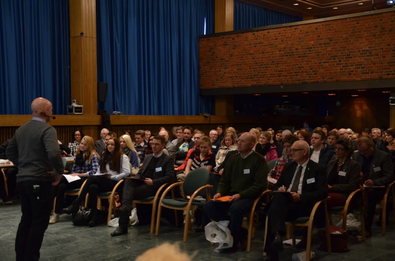 a crowd of people seated in a auditorium and speakers