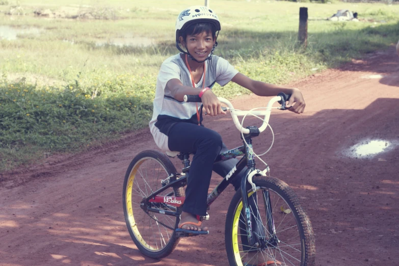 a woman sitting on top of a bicycle on a dirt road