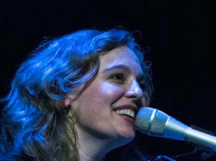 a woman in black is singing into a microphone