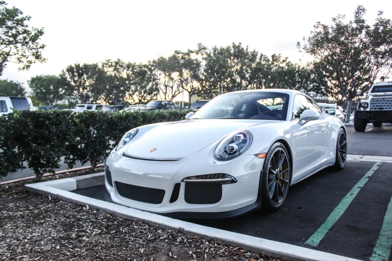 the white porsche is parked next to a fence