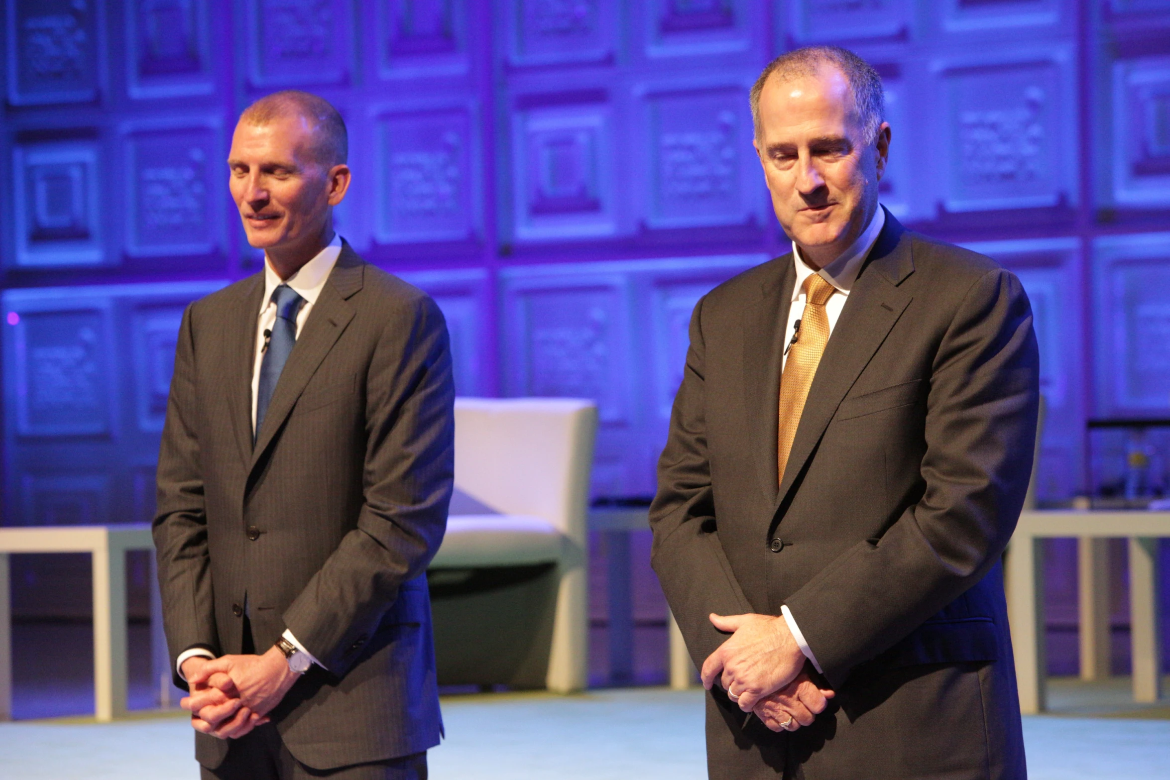 two older men standing in suits and ties