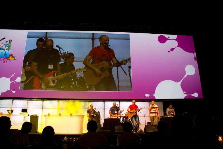 a band playing on stage under a large video screen