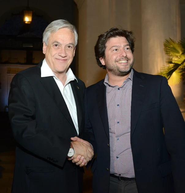two men shake hands before a night at an event