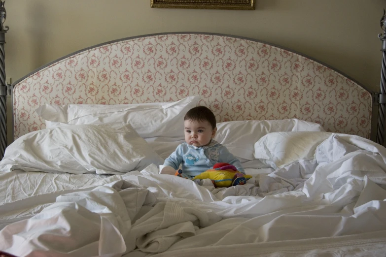 a small child with a yellow stuffed animal on top of a bed