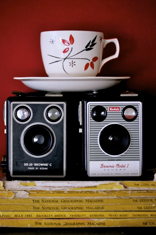 an old camera sits in front of a plate and cup on top of some books