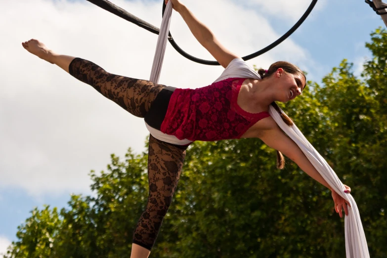 a woman does aerial gymnastics in front of some trees