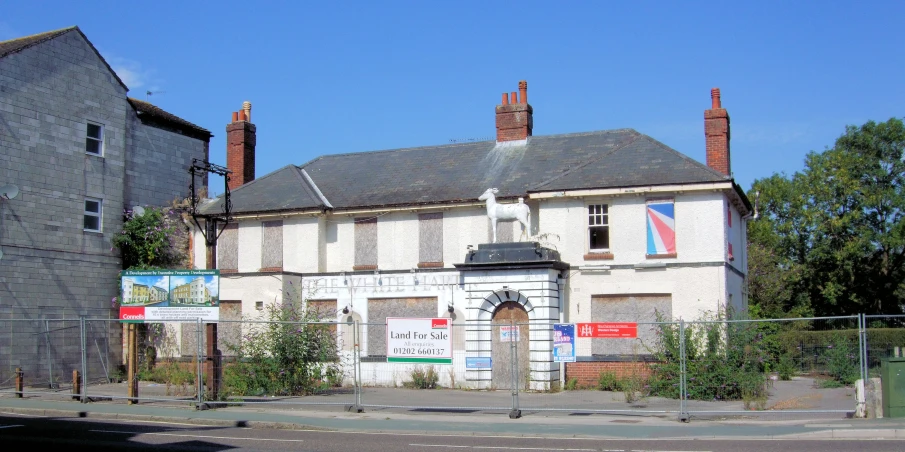 a vacant, boarded up building sits along the street