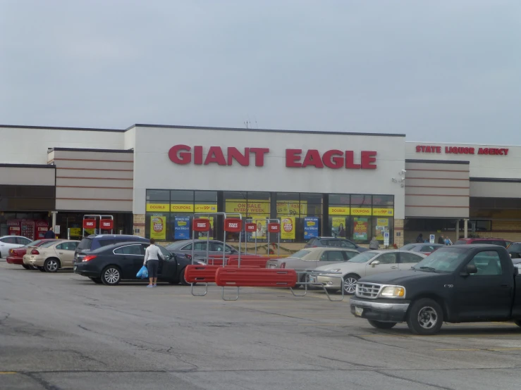 many parked cars are sitting outside of a giant eagle store